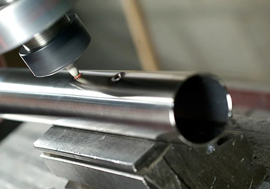 Eine Maschine bohrt ein Loch in ein Metallrohr. Eine Maschine bohrt ein Loch in ein Metallrohr.