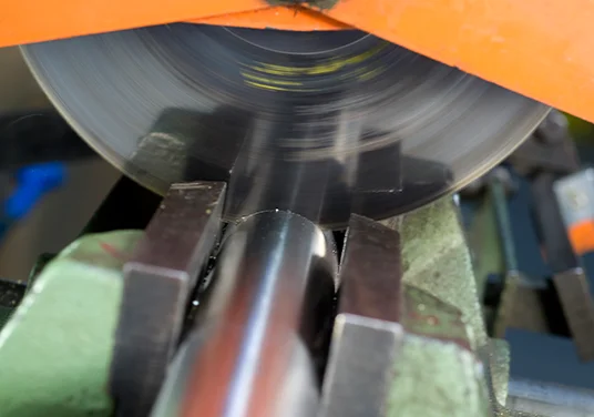 Ein Edelstahlrohr wird mit einer Säge in zwei Teile gesägt und leichte Funken sprühen. Ein Edelstahlrohr wird mit einer Säge in zwei Teile gesägt und leichte Funken sprühen.